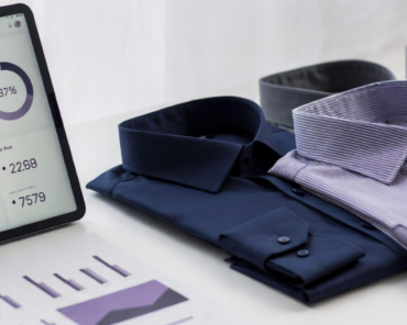 Fashion PLM dashboard displayed next to folded shirts and sourcing performance reports.